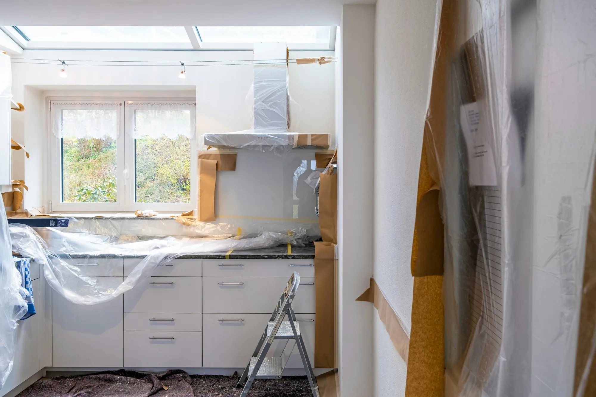 Kitchen cabinets wrapped in plastic sheeting during a renovation