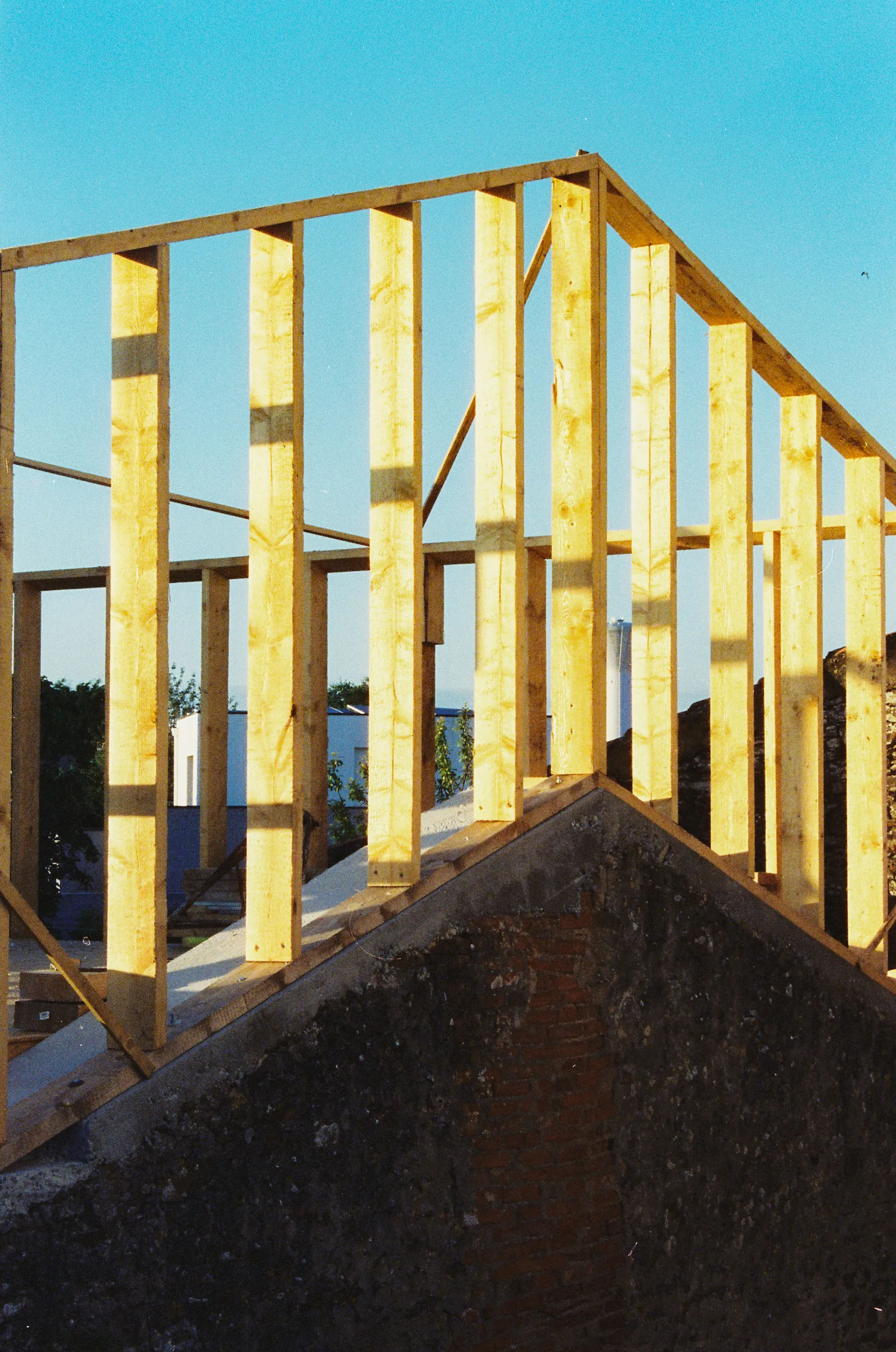 New second-story wall framing rising above an existing gable